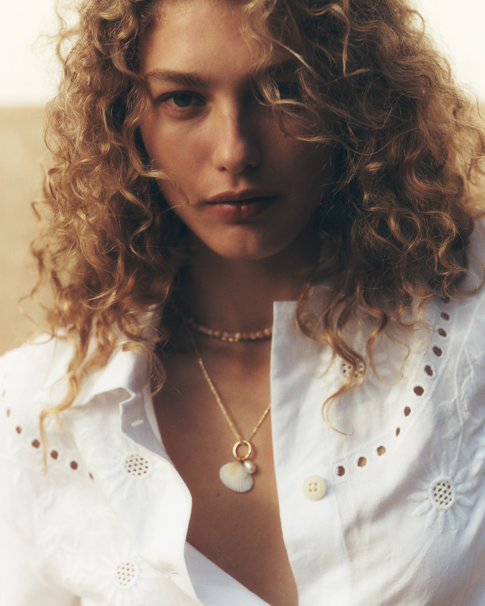 Curly-haired woman in white eyelet shirt